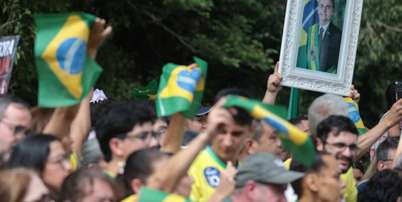 Apoiadores de Flávio Bolsonaro acenam com bandeiras do Brasil e quadro de Jair antes de carreata em Santa Bárbara d'Oeste Foto: Felipe Rau/Estadão