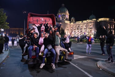 A group of people sitting on the back of a truck, celebrating