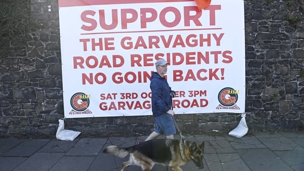 A man walks a dog past a community event sign in support of the Garvaghy Road